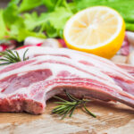 raw lamb chops with spices and herbs close up on wooden background