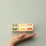 wooden blocks with different emotions from smile to sadness and woman s hand concept for assessing the quality of product or service emotional state user reviews
